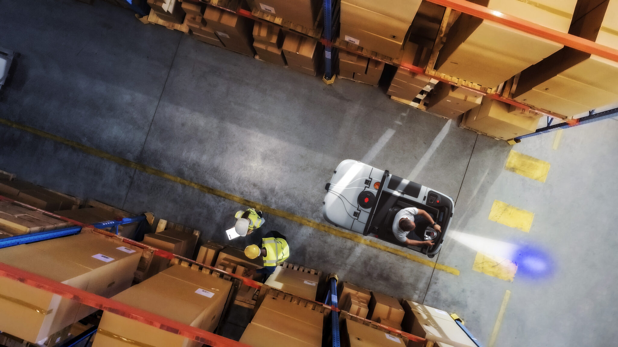 top down view: workers stand in rows of shelves with goods in retail warehouse, use digital tablet and talk about package delivery. people work in product distribution logistics center